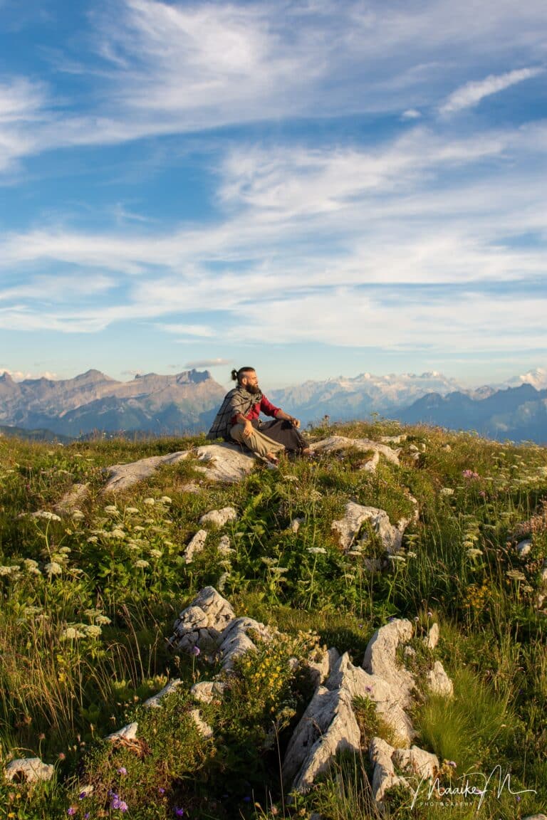 Man sitting in the mountains and enjoying the view over the Alps during a portrait session nearby Leysin in Switzerland
