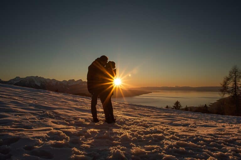 Couple kissing in front of sunset during a winter portrait session nearby Montreux