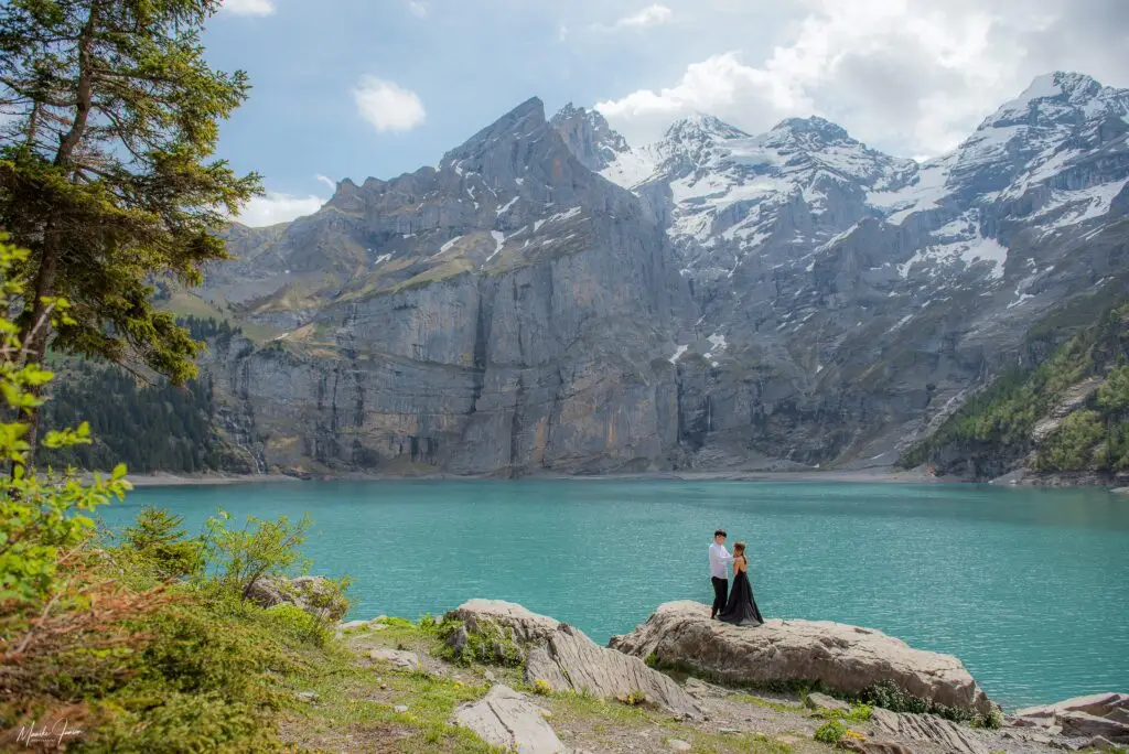 Asian couple holding eachother while enjoying a view over the Oeschinensee in Switzerland.