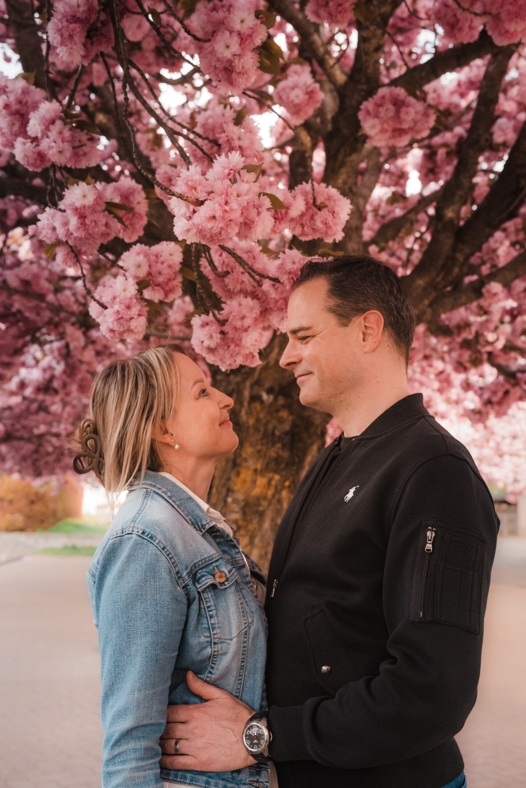 Couple looking at eachother under an apple tree in blossom during a photosession in Switzerland