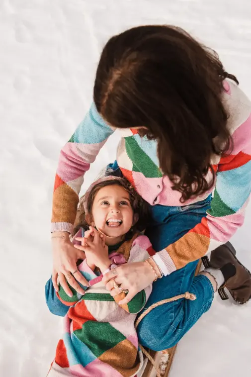 Young child looking at her mom and laughing during a winter family portrait session near Montreux