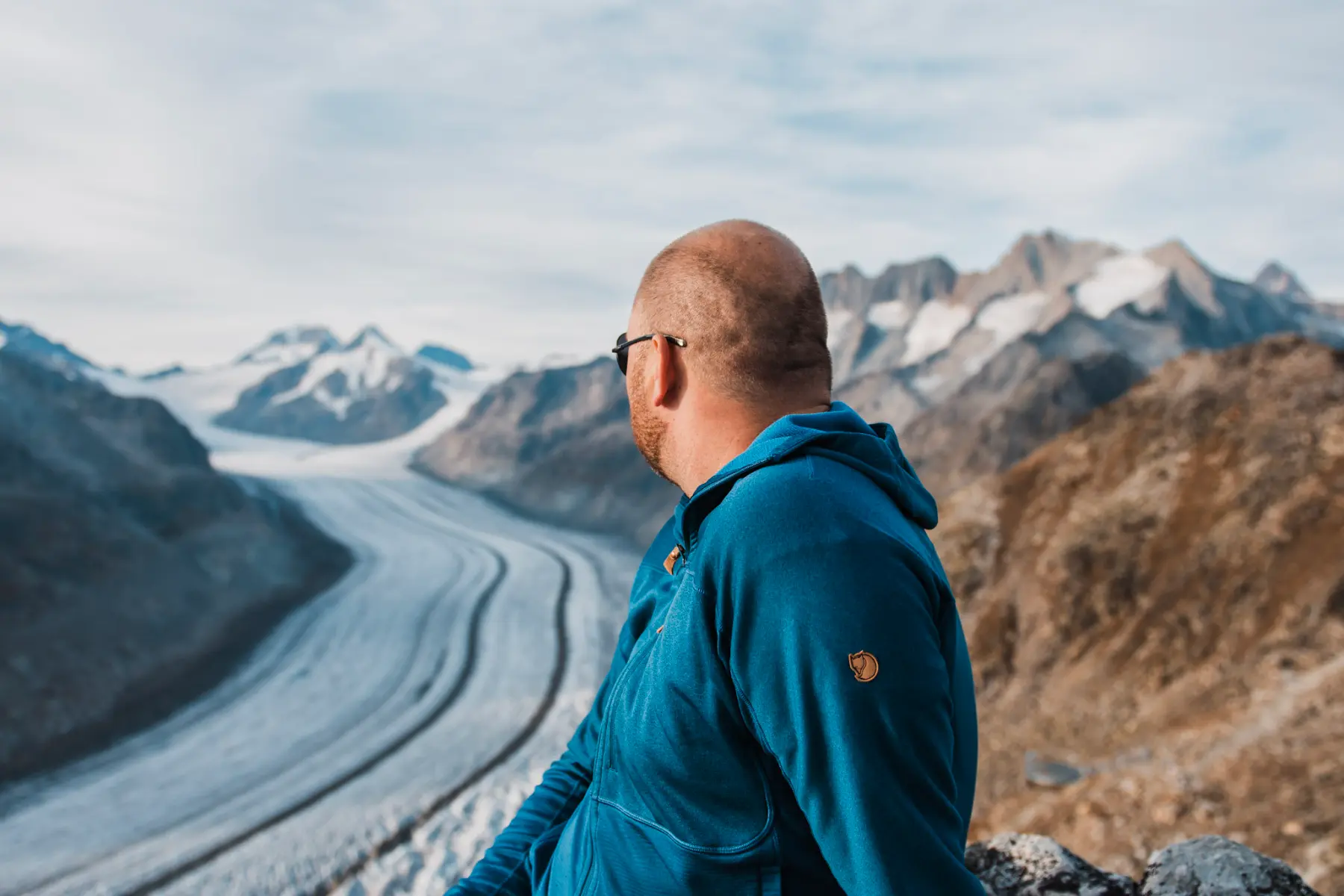 man looking at a massive glacier in switzerland during a portrait session