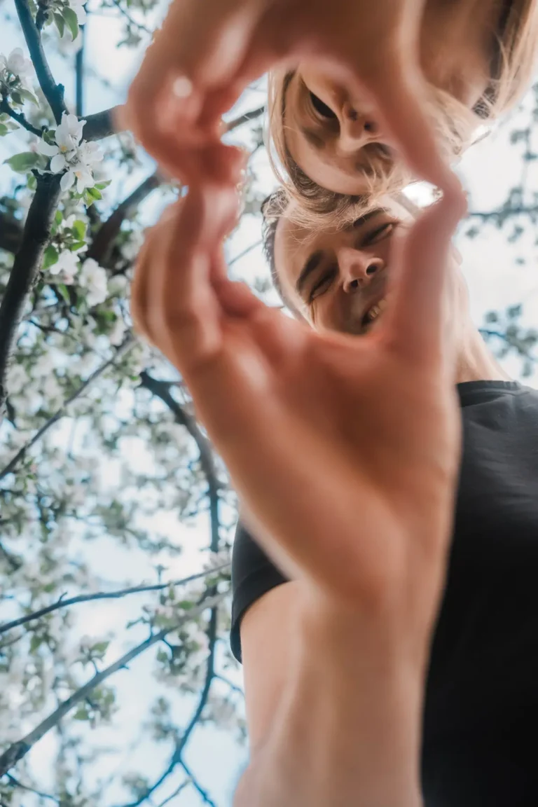 couple smiling while holding hands in heart shape