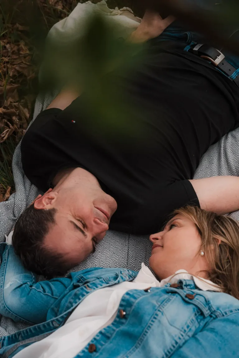 couple facing eachother while laying on a blanket during a romantic portrait session outdoors