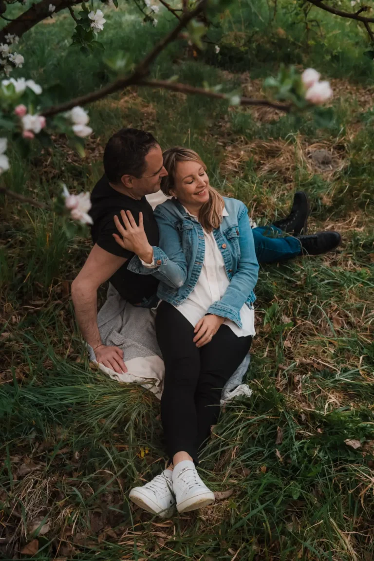 couple sitting on a blanket under an apple tree