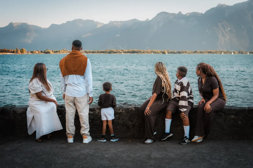 Parents and their four children sharing a relaxed moment with Château de Chillon and Lake Geneva in the background.