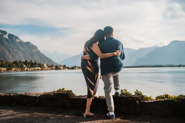 Newly engaged couple embracing with Lake Geneva beside Château de Chillon